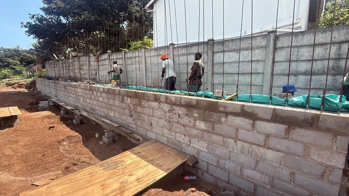 Crew placing concrete infill into the reinforced masonry wall cavity.