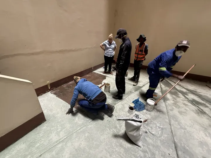 Crew preparing the floor surface in the Amanzimtoti interior before epoxy application.