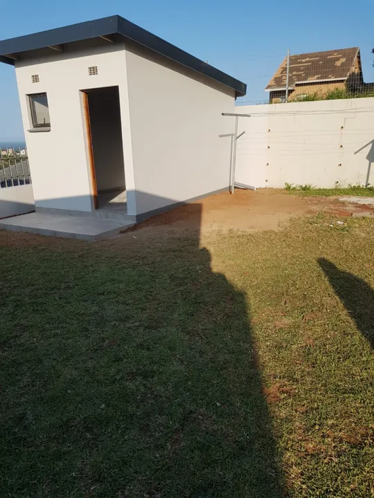 Completed storage building in Tongaat showing the painted exterior, roof, window and tiled entrance beside the lawn.