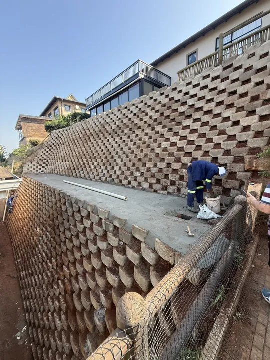 Tall terraced block retaining wall with crew working beside the lower terrace.