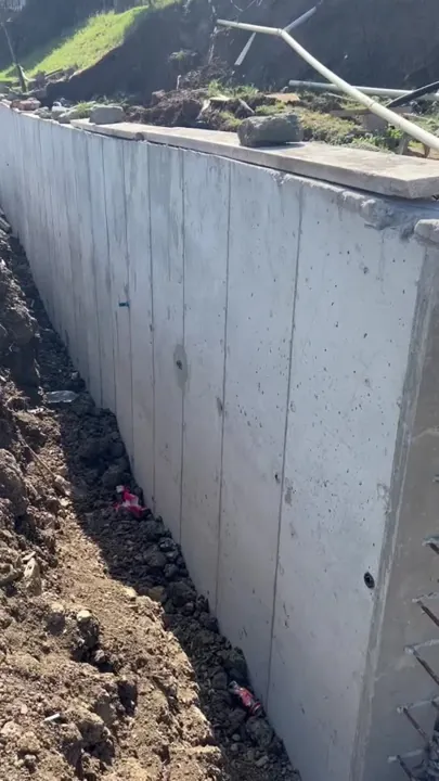 Exposed concrete wall after formwork removal with surrounding ground still unfinished.