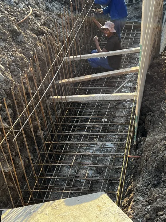Steel reinforcing cage within the excavated wall foundation trench.