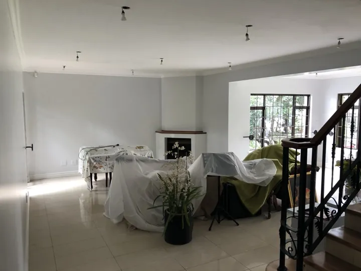 Painted lounge with covered furniture and interior painting work still underway.