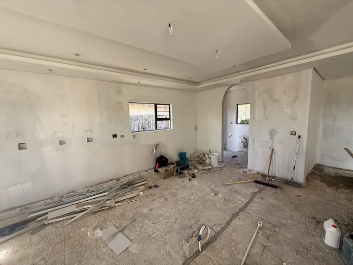 Interior work area with unfinished walls, ceiling work and construction materials.