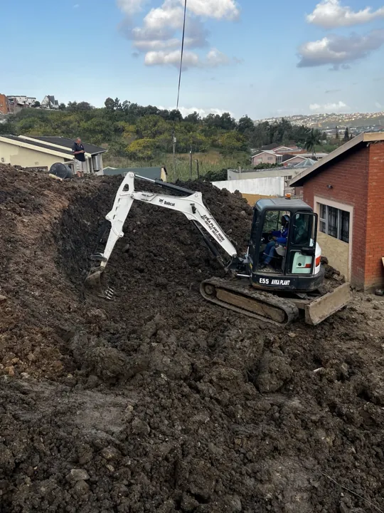 Excavator working on the earth bank before wall construction.