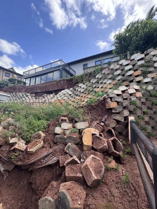 Existing collapsed retaining blocks below the remaining terraced wall before rebuilding.