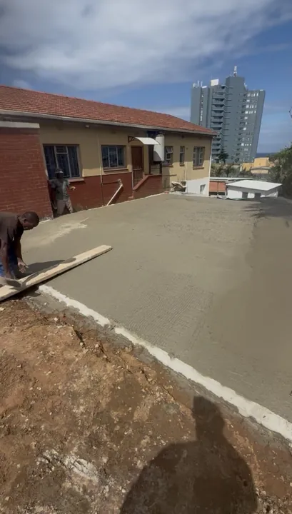 Freshly placed garage floor slab with a worker finishing the concrete surface.
