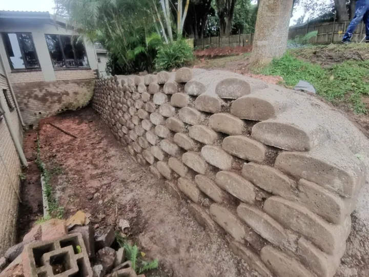 Small block retaining wall beside a house and garden.